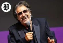 : Al Pacino laughing while holding a microphone during a live interview.