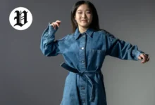 Woman posing in a belted long-sleeve denim dress outfit.