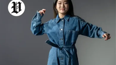 Woman posing in a belted long-sleeve denim dress outfit.