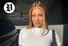 Kylie Jenner posing in natural sunlight wearing a white fitted top.
