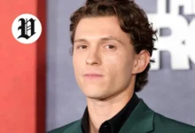 Tom Holland posing on the red carpet in a dark green suit