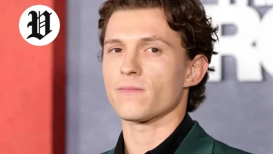 Tom Holland posing on the red carpet in a dark green suit