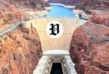 Aerial view of Hoover Dam with rugged red rock cliffs and the Colorado River below.
