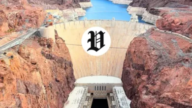 Aerial view of Hoover Dam with rugged red rock cliffs and the Colorado River below.