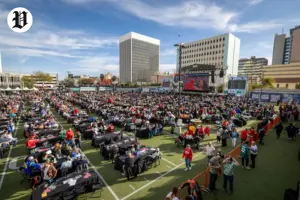 Large crowd seated at an outdoor Super Bowl watch parties in Las Vegas with stadium-style big screens.