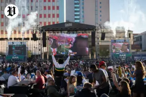 Fans cheering during a Super Bowl watch parties in downtown Las Vegas with a giant outdoor screen showing the game