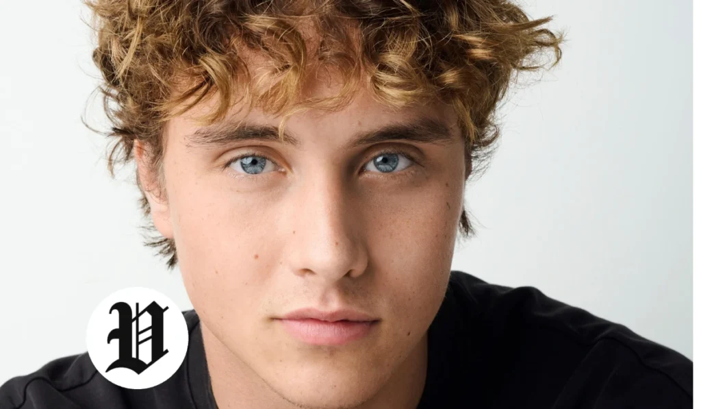 Close-up portrait of Joseph Zada with curly blond-brown hair and bright blue eyes against a light studio background.