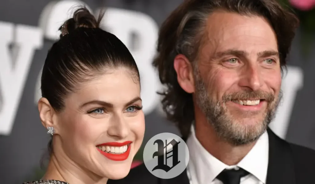 “Alexandra Daddario smiling brightly next to a man in a suit at a red-carpet event.”